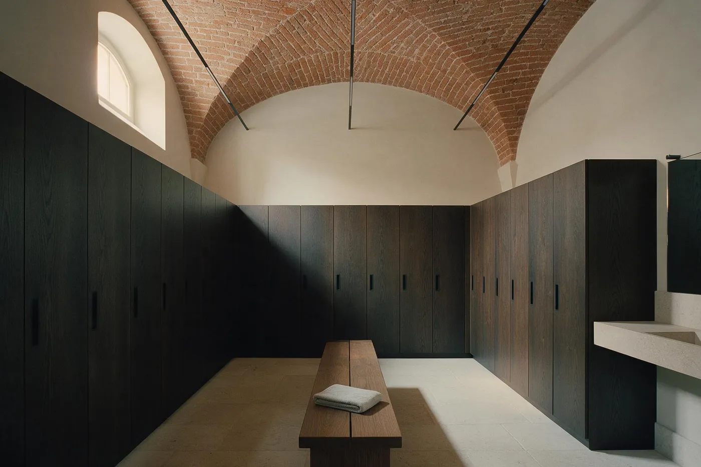 Gli spogliatoi con gli armadietti in rovere scuro e la panca centrale.